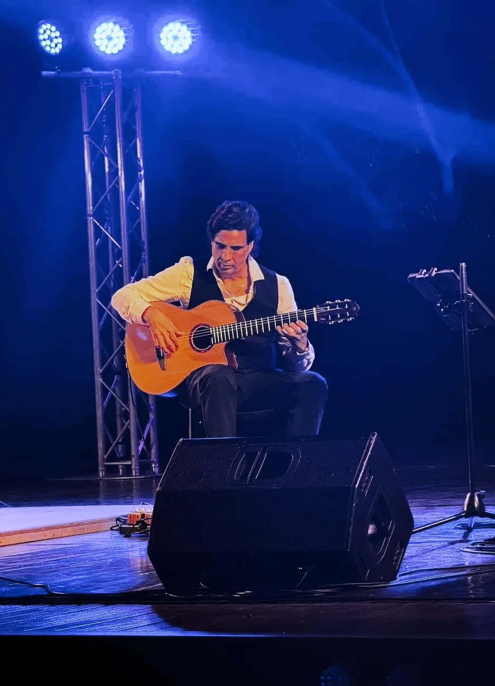 Ernesto Castillo performing solo on a concert stage under blue light