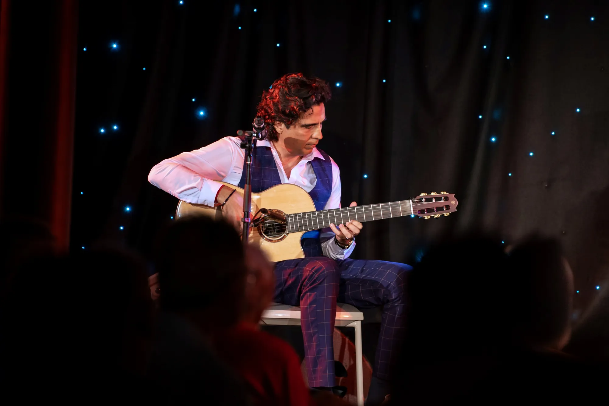 Latin guitarist Ernesto Castillo performing on stage under a starry curtain