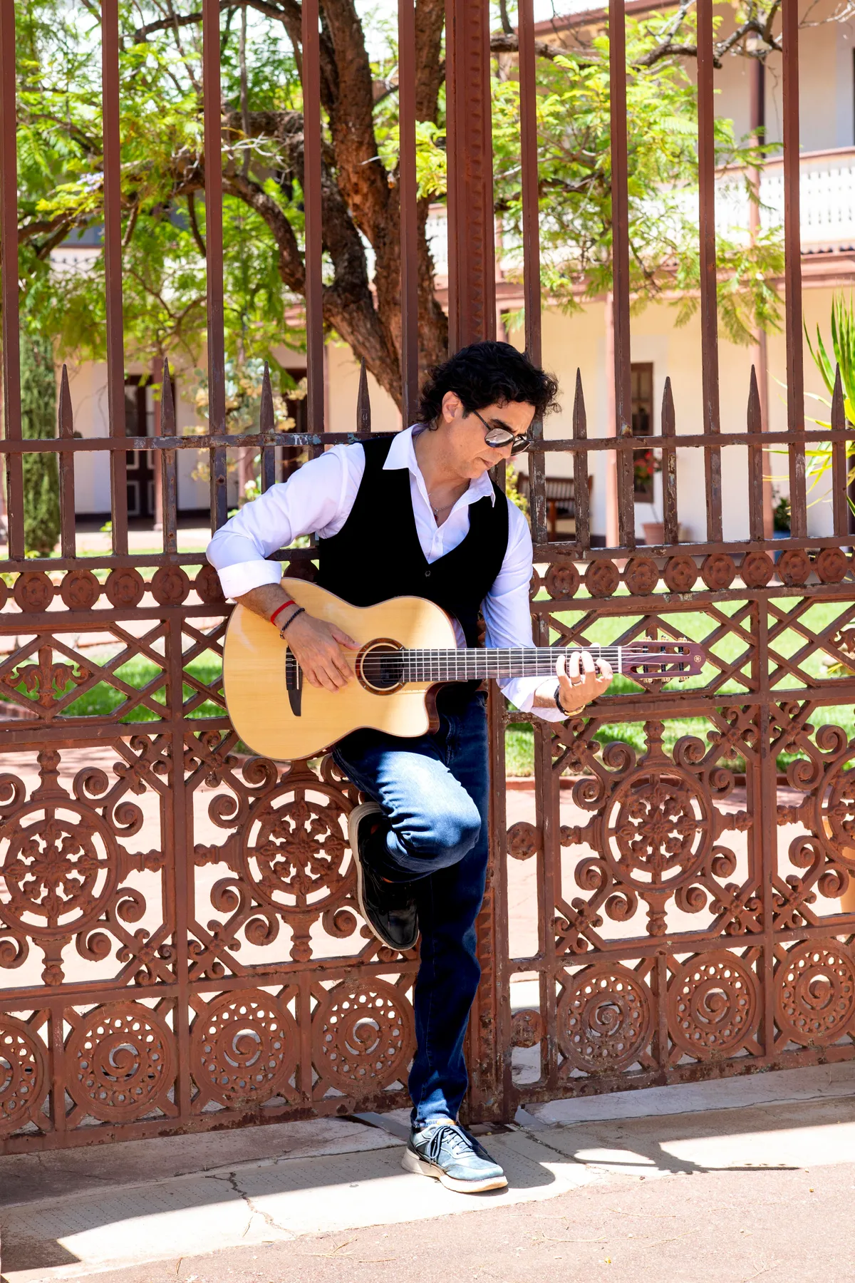 Ernesto Castillo with guitar by an ornate gate