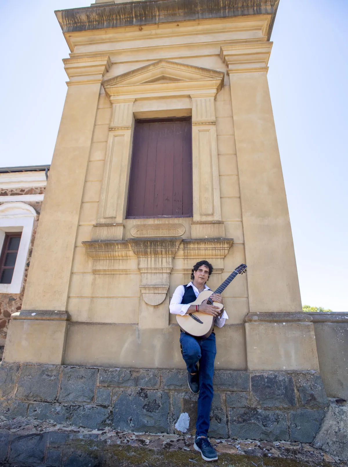 Ernesto Castillo with guitar at the foot of a sandstone tower