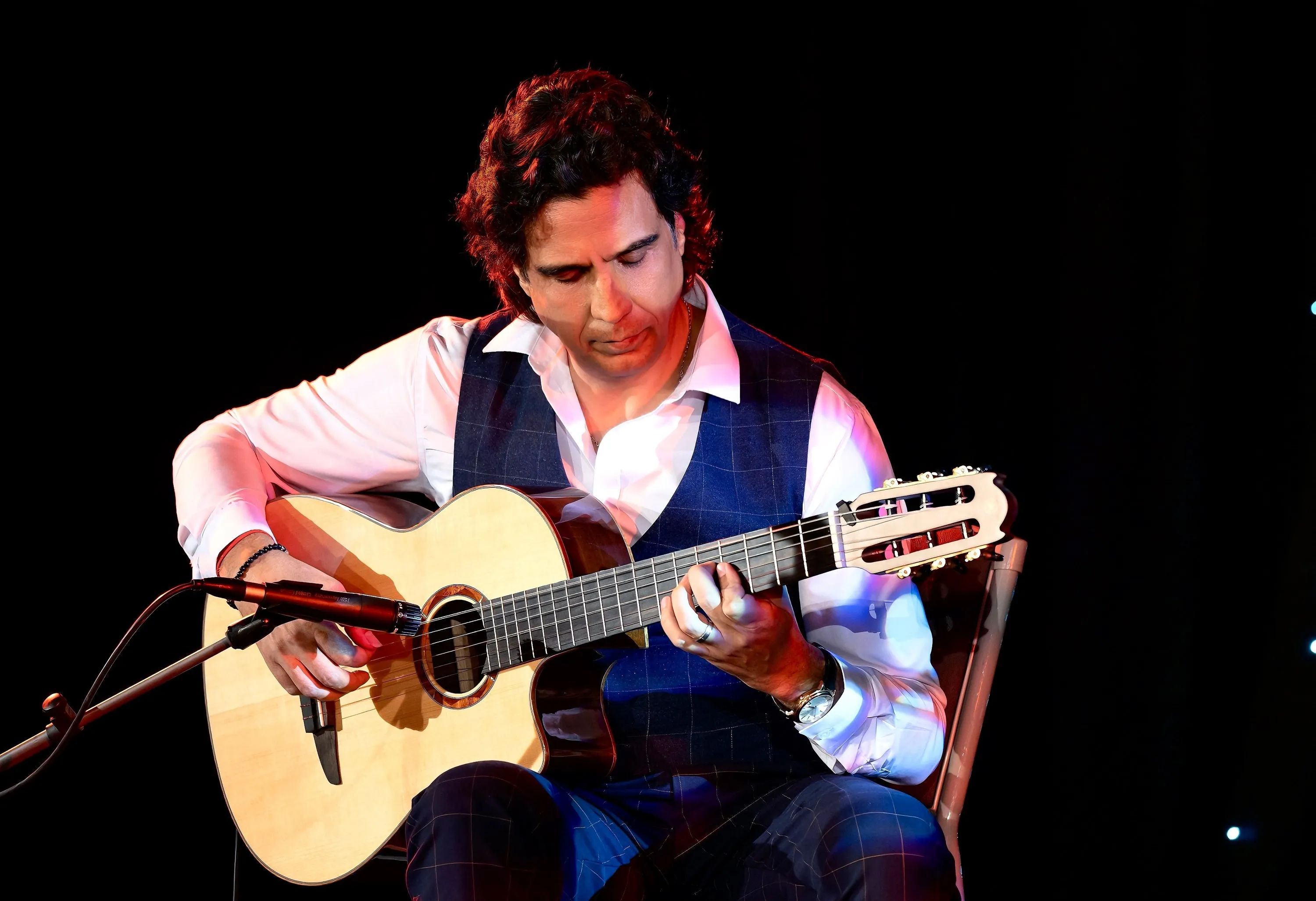 Ernesto Castillo playing nylon-string guitar on a dark stage