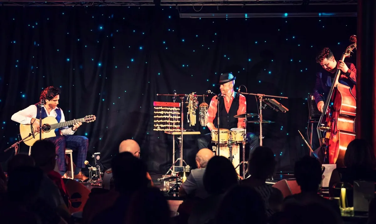 Ernesto Castillo with percussion and double bass under a starry backdrop
